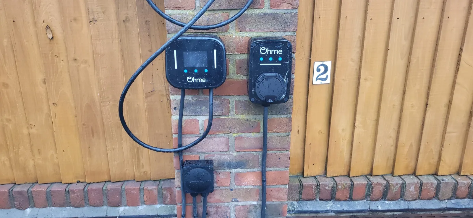 Outdoor weatherproof sockets and an EV charge point installed on a fence and brick wall